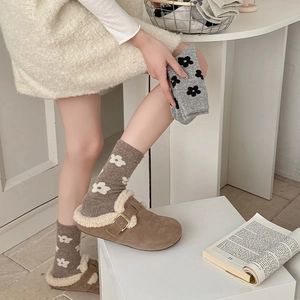 Detail of wool socks with flower patterns and warm fleece-lined slippers for winter