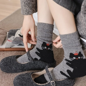 Close-up of grey knit mid-tube socks featuring black cat patterns and soft texture