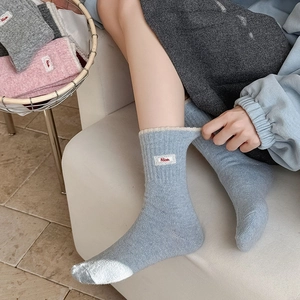 Détail de chaussettes en tricot à mi-mollet avec broderie Nice et bords côtes doux