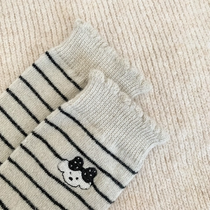 Détail de chaussettes rayées en laine avec bords volantés et broderie de petit chiot