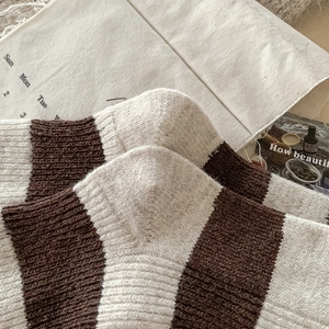 Gros plan de chaussettes en laine à rayures marron et crème avec texture tricotée épaisse