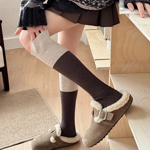 Detail of color-block wool socks featuring ribbed texture and warm brown-oatmeal split