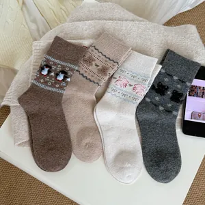 Close-up of four thick knit crew socks with cartoon bear penguin and cat patterns