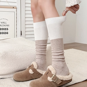 Detailed close-up of knitted two-tone wool socks paired with fur-lined mules and buckles