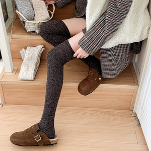 Close-up of thick knitted over-the-knee socks in dark grey and oatmeal winter textures