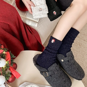 Detail of Christmas Santa embroidery on thick blue wool socks with felt mule slippers