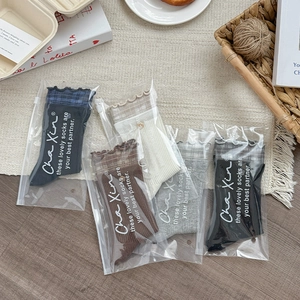 Detail of five pairs of plaid ruffle trim cotton socks in individual packaging