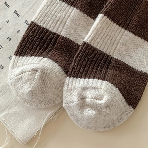 Gros plan de chaussettes en laine à rayures marron et blanc avec texture côtelée épaisse