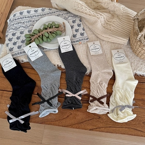 Flat lay of ballet-style slouch socks in five colors with ribbon bows and ruffle details