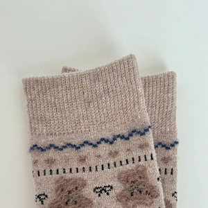 Close-up of khaki winter socks featuring knitted bear patterns and ribbed cuffs