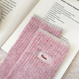 Détail de chaussettes en laine rose avec dentelle et écussons brodés Nice rouges