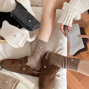 Close-up of wool knit socks with shell buttons and metallic accents worn with mule shoes