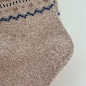 Macro shot of thick knitted wool socks showing soft texture and Fair Isle geometric patterns