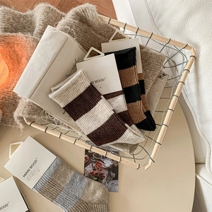 Détail de chaussettes en laine à rayures colorées disposées dans un panier métallique