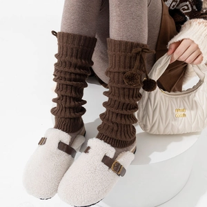 Dettaglio di scaldamuscoli in maglia a coste marroni con pompon per un look invernale