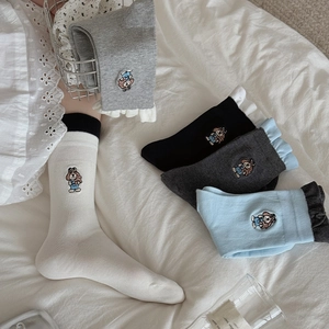 Close-up of cute puppy embroidery and ruffled edges on colorful cotton mid-tube socks
