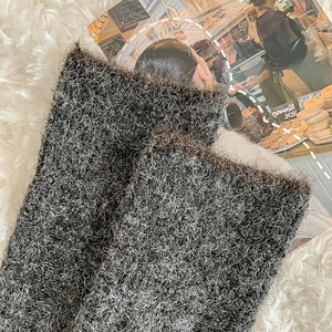 Close-up of thick charcoal grey knitted leg warmers with fuzzy mohair texture