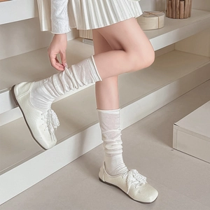 Close-up of white knitted slouch socks paired with lace-up leather ballerina flats