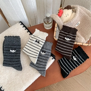 Gros plan de la broderie de chiot et des bords ondulés sur les chaussettes en laine