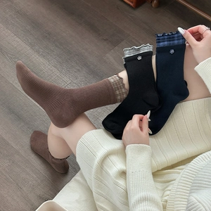Detail of ruffled plaid edge socks with small flower accent on navy, black and brown knit