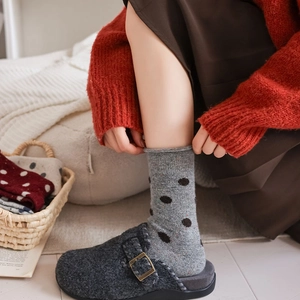 Detail of wool blend polka dot socks with rolled cuffs paired with felt clogs