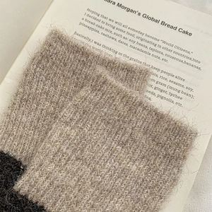 Nahaufnahme warmer flauschiger Overknee-Socken mit zweifarbiger Textur auf Vintage-Buch