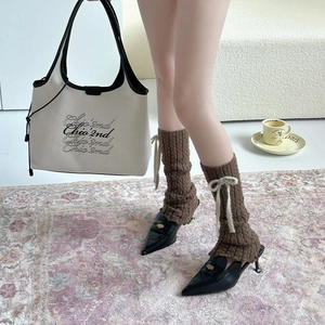 Brown cable knit leg warmers with white bows styled with black pointed mule heels
