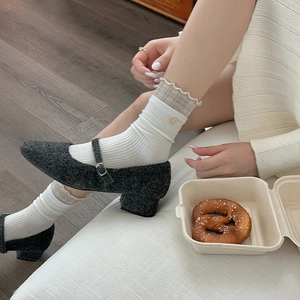 Close-up of grey wool Mary Jane heels with button strap and white knitted socks