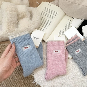 Détail de chaussettes en laine avec écusson en dentelle brodée et étiquette sur fausse fourrure