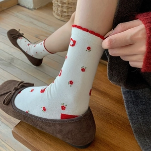 Detail of floral knit socks with red ruffled edges paired with brown ballet flats
