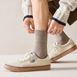 Close-up of khaki ribbed wool socks paired with white canvas shoes on a model