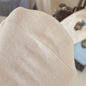 Macro shot of cream rib knit fabric showing detailed stitching and soft warm texture