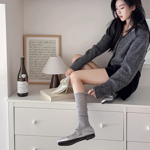 Detail of grey slouch socks paired with silver Mary Jane shoes and a knit cardigan