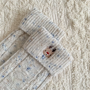 Close-up of thick knit wool socks featuring reindeer embroidery and fold-over cuffs
