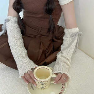 Detail of cream white knit leg warmer featuring hollow weave texture and gray plush bow tie