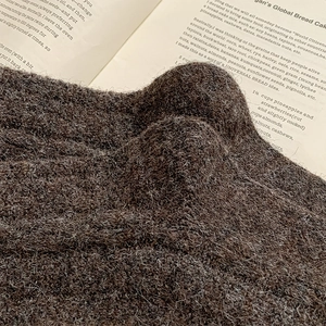 Makroaufnahme von dunkelbraunem Strickgewebe mit warmen Wollfasern und Vintage-Stil