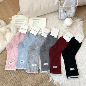 Chaussettes en laine colorées avec dentelle et broderie sur un tapis en fourrure blanche