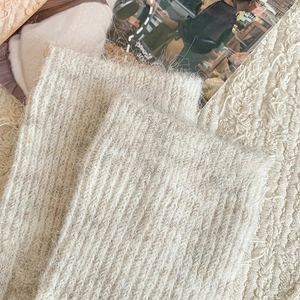 Detailed close-up of creamy beige cable knit over-knee socks with soft fuzzy texture