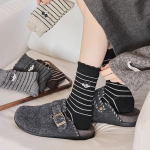 Détails de chaussettes rayées chaudes avec broderie et mocassins en laine cozy