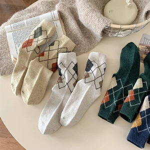 Detailed knit texture of vintage argyle wool socks in warm cream and navy blue colors