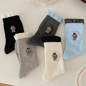 Detailed close-up of cute cartoon dog embroidery and ruffled lettuce edges on five crew socks