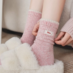 Détail de chaussettes en laine rose tricotée avec bordure dentelle et broderie Nice