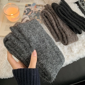 Close-up of thick knitted winter neck warmers in grey, brown and black colors