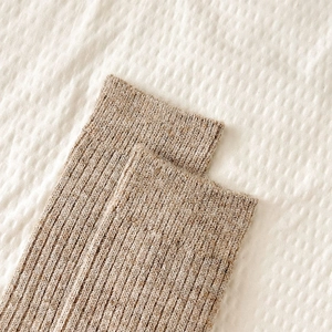 Detail of ribbed knit cuffs on thick oatmeal wool socks for winter warmth and comfort