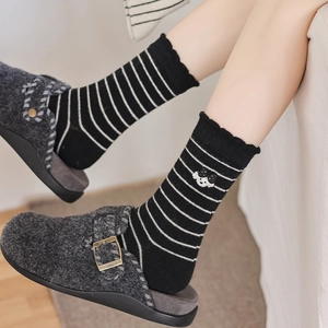 Chaussettes rayées avec broderie chien portées avec sabots en feutre sur parquet
