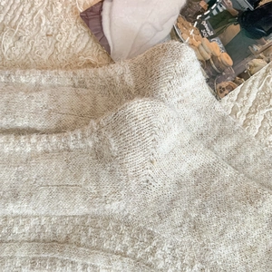 Close-up of cream knit over-knee socks featuring thick warm fuzzy texture and soft wool