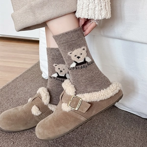 Close-up of cute teddy bear wool socks and cozy brown suede slippers with fleece lining
