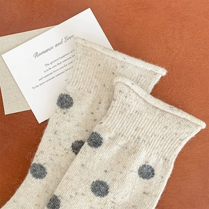 Detail of wool knit crew socks with grey polka dots and rolled cuff on a warm background