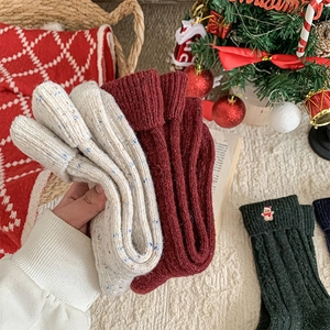 Close-up of thick knitted Christmas wool socks with festive embroidery in warm setting