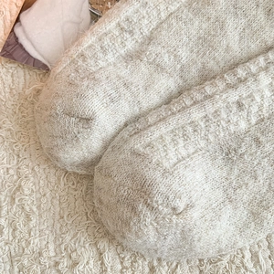 Detail of soft cream white knit over-knee socks featuring thick thermal plush texture
